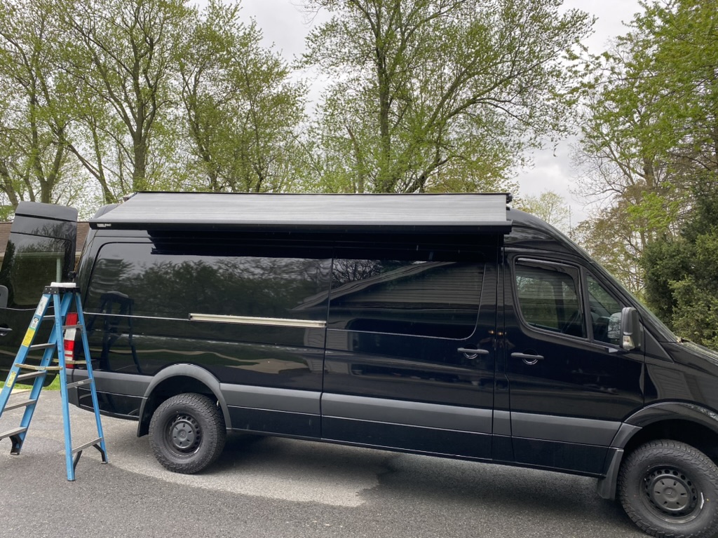 Black Keystone Sprinter with its full-length exterior awning deployed
