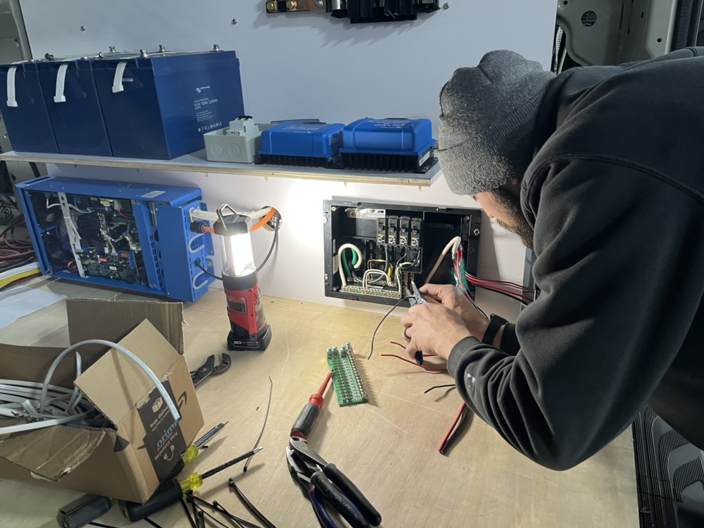 Builder wiring a control panel inside a Keystone van